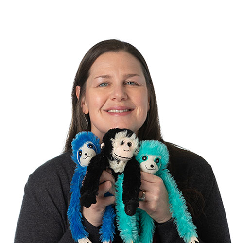 trista smith team member at orases holding three small monkey plushes