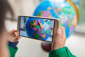 kid playing augmented reality popup globe with dinosaurs via mobile