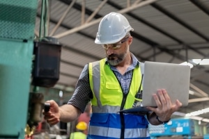 factory worker looking at the state of their machinery using equipment monitoring software