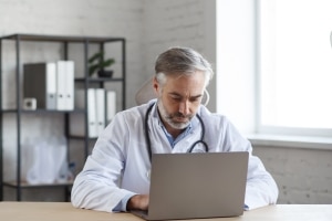 medical professional using his laptop to access recently uploaded electronic health patient records