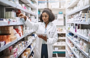pharmacist looking through the aisles and recording information on their tablet