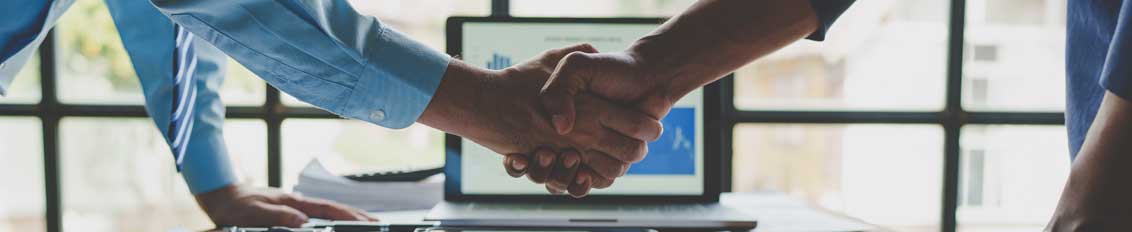 Insurance broker shaking hands with a custom insurance ERP software developer over table