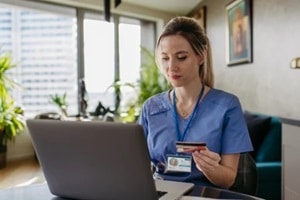 nurse paying bills online with debit or credit card, working on notebook