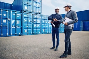 smiling engineers shaking hands together in a shipping yard