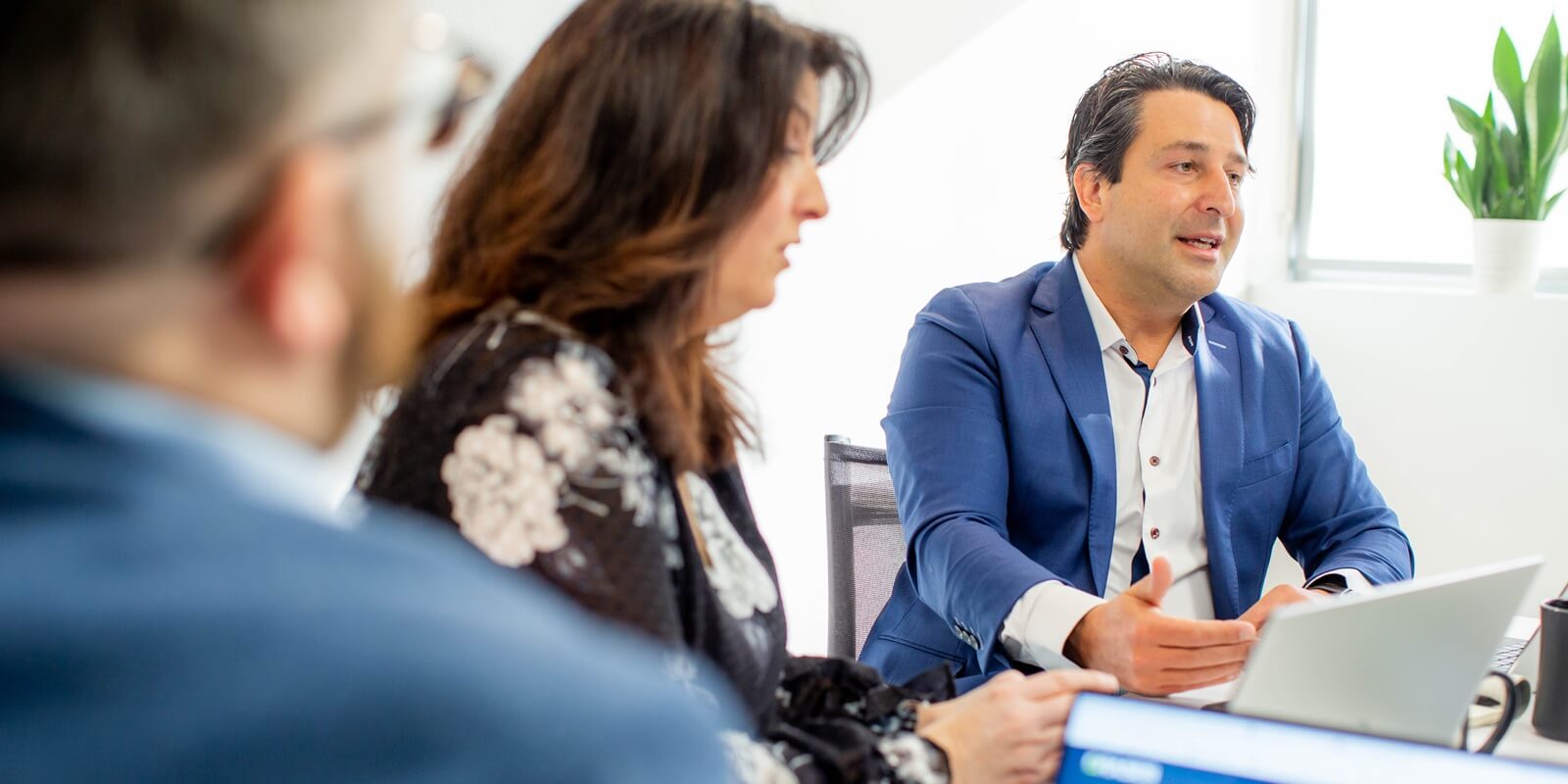 business professionals engaged in a discussion during a meeting, with one person actively presenting while others listen and take notes
