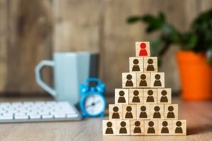 wooden cubes with men lined up with a pyramid on the background of the office desk