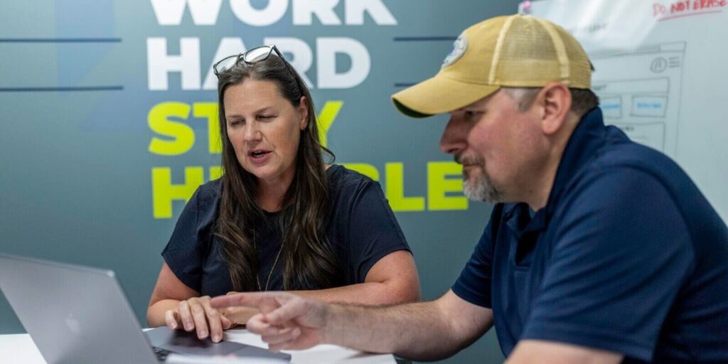 orases two employees discussing something on a laptop