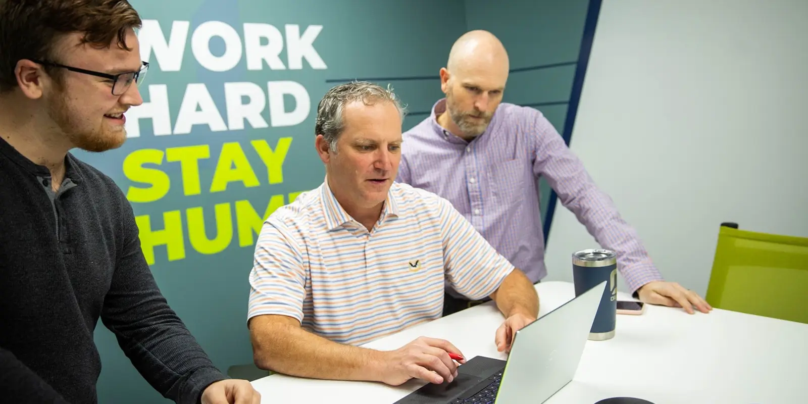 three male employees working on a laptop