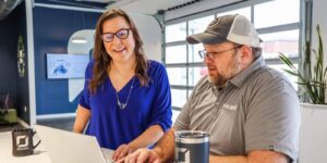 two orases members smiling and working on a laptop